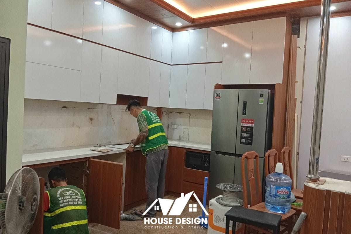 : Thợ lành nghề đang lắp đặt hệ tủ bếp hiện đại và sơn lại tường căn hộ, thuộc nhóm hạng mục sửa chữa không ảnh hưởng kết cấu.