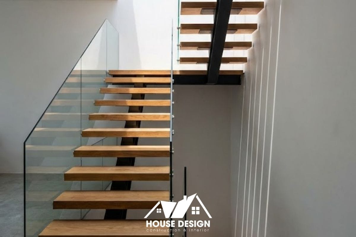 Cầu thang xương cá với bậc gỗ và lan can kính cường lực giúp ánh sáng từ giếng trời xuyên qua các tầng.