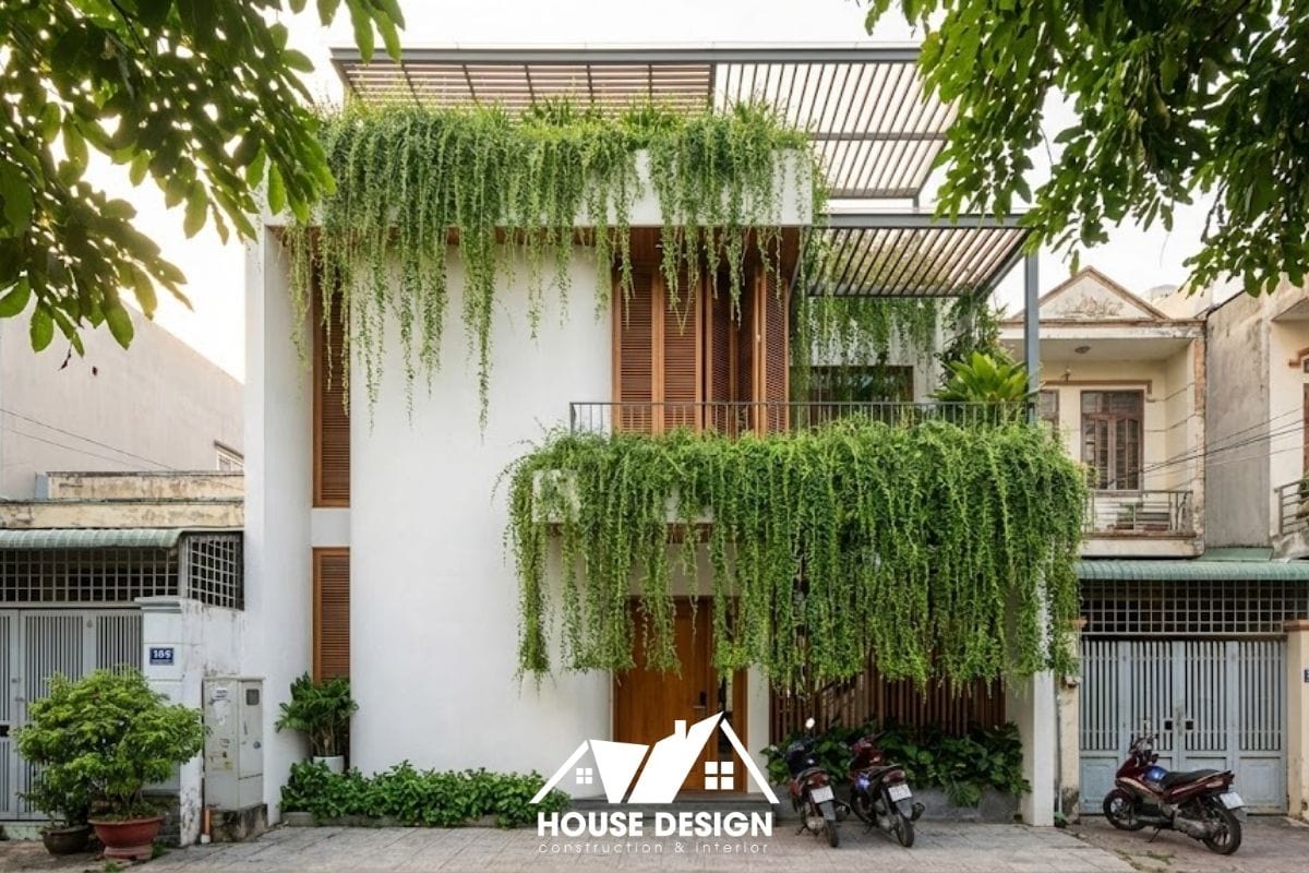 Mặt tiền nhà ống 2 tầng lột xác với hệ lam kết hợp cây dây leo rủ xuống như một tấm rèm thiên nhiên xanh mát.